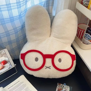 Detail of plush cream bunny hot water bottle with red glasses in cozy home setting