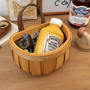 Detail of hand-woven wooden storage basket with leather handle and French vintage print