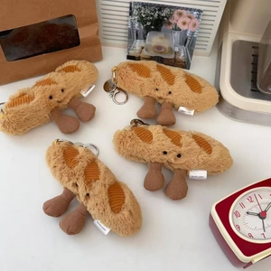 Detailed view of plush baguette charms with smiling faces and metal keychains