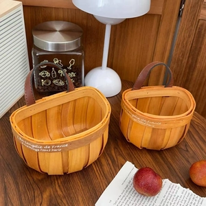 Detail of handwoven wooden storage baskets with leather handles in a home setting