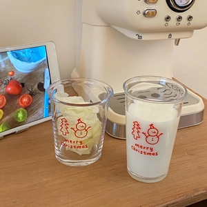 Christmas snowman glass cup set with red festive prints on a warm wooden tabletop