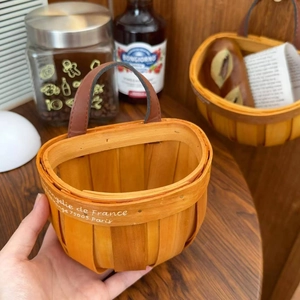 Detail of hand-woven wood storage basket with vintage French print and leather handle