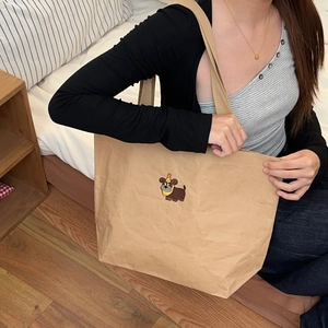 Detail view of khaki kraft paper tote bag featuring cute dog embroidery and durable straps