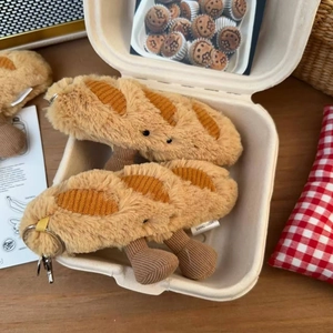 Close-up of plush baguette keychains with embroidery detail in a cozy paper box