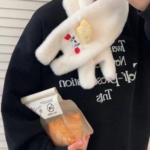 Détail d'une écharpe en peluche crème avec pendentifs fromage et bonbons et texture douce