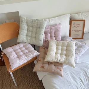 Detail of square quilted floral seat cushions with white ties on a wooden chair