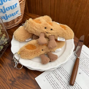 Close-up of plush baguette bag pendant with metal keychain and woven label on a plate