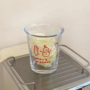 Detail of Christmas snowman and tree pattern printed on clear glass coffee mug