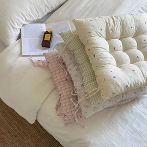 Close-up of floral seat cushions with straps and quilted texture on a white bed