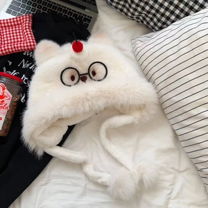 Détail du bonnet peluche crème avec patch lunettes noires et pompons cerise rouges