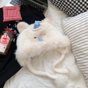 Vue détaillée du bonnet chat blanc en peluche avec oreilles bleues et pompons doux