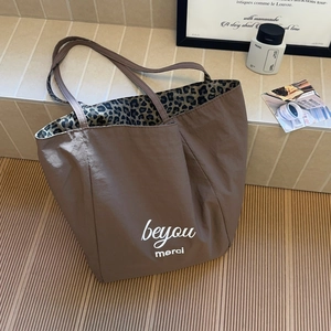 Detailed view of brown tote bag with white text and stylish leopard print inner lining