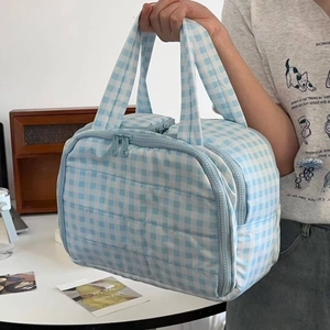 Blue gingham quilted cosmetic bag with dual handles and secure zipper closure