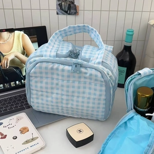 Detail of blue checkered quilted makeup bag showing spacious interior mesh compartment