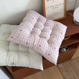 Detailed view of quilted square floral seat cushions with straps on a wooden shelf