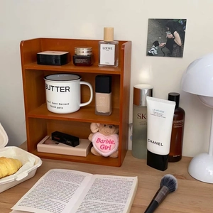 Two-tier wooden desktop organizer shelf with skincare products in a cozy home setting