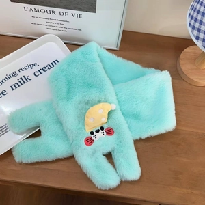 Détail d'une écharpe en peluche vert menthe avec accessoire d'ours blanc sur table en bois