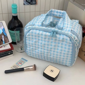 Detail of blue checkered quilted makeup bag with zipper closure and portable handle