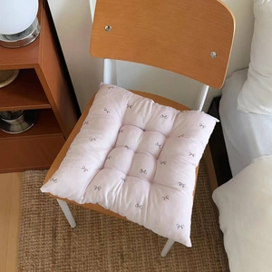 Detail of pink floral seat cushion with bow patterns and securing straps on a chair