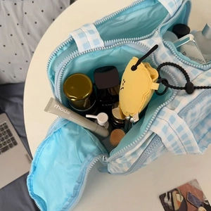 Top view of blue gingham cosmetic bag showing large interior storage for skincare bottles