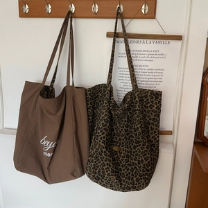 Detail of leopard print tote and solid brown canvas bag with artistic lettering