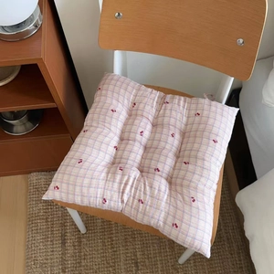 Close-up of pink checkered chair cushion with cherry prints on a wooden chair