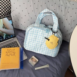 Blue plaid quilted cosmetic bag with yellow smiley charm in a home lifestyle setting
