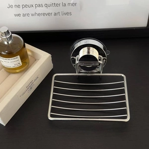 Detail of wall-mounted stainless steel soap dish with suction cup on wooden surface