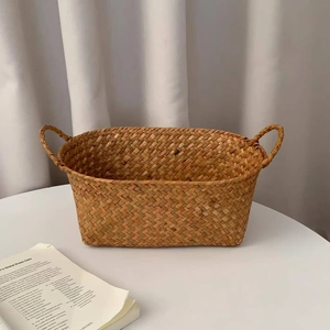 Close-up of hand-woven natural fiber basket with handles on a white tabletop