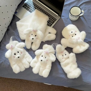 Detail of plush white puppy gloves and scarf set on a cozy bed with coffee cup