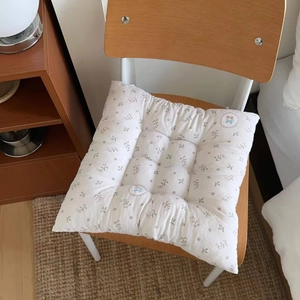 Close-up of a square quilted floral chair cushion with straps on a wooden seat