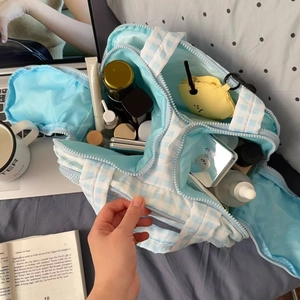 Detailed interior of blue checkered makeup bag showing dividers and high storage capacity