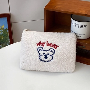 Detailed embroidery on white teddy fleece cosmetic bag featuring a cute cartoon bear motif