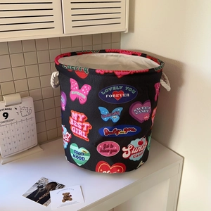 Close-up of black canvas laundry basket featuring colorful graffiti art and rope handles