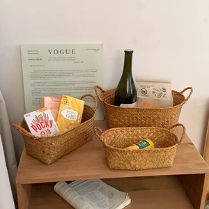 Detailed view of three nested woven storage baskets with handles on a wooden shelf