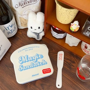 Macro shot of toast-shaped sandwich box with a spreading knife on a wooden table