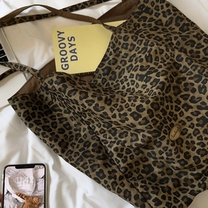Close-up of leopard print tote bag with a metallic Handmade tag on canvas surface