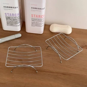 Macro detail of two stainless steel wire soap holders in rectangular and curved shapes
