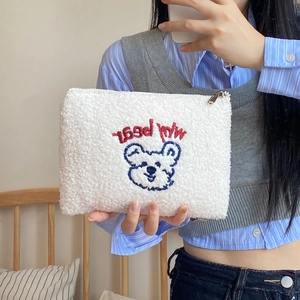 Detail of embroidered cartoon bear on white plush makeup bag with My Bear text