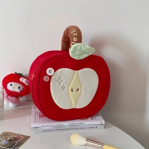 Detail of red apple plush storage bag with sequin stars and soft velvet texture