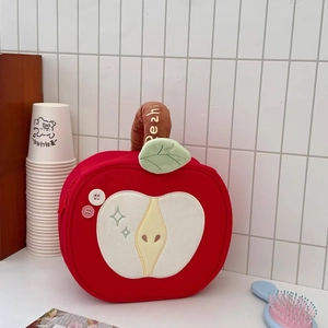 Detail of red apple-shaped makeup bag with creative embroidery and handle texture