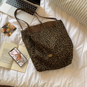 Detail of leopard print tote bag featuring a handmade metallic logo on canvas fabric