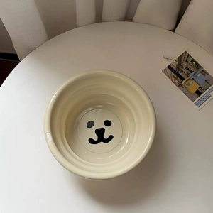 Close-up of a cream-colored washbasin featuring a cute cartoon bear face print detail