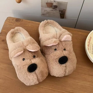 Detalle de pantuflas de perro de felpa marrón con forro cálido en fondo de madera