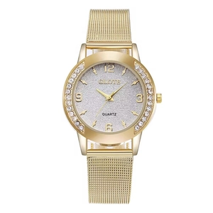 Detailed close-up of a women's gold mesh strap watch with a rhinestone-studded bezel