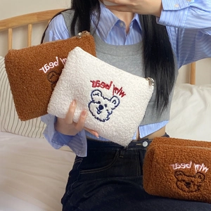 Detail of embroidered teddy bear cosmetic pouch in soft sherpa fleece fabric texture