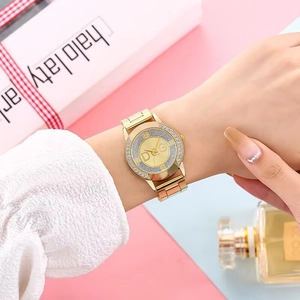Close-up of golden women's watch with rhinestone bezel and luxury metal link bracelet