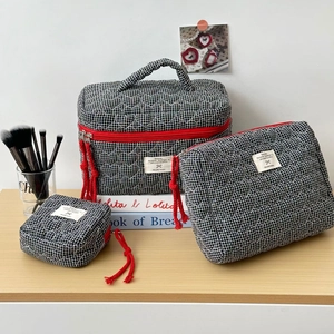 Ensemble détaillé de trois trousses de maquillage matelassées à carreaux noirs et zips rouges