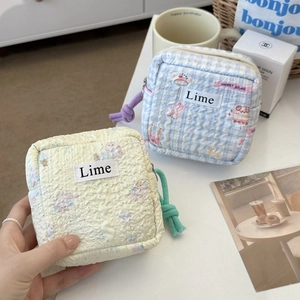 Detail of quilted seersucker makeup bags in floral and plaid patterns with Lime label