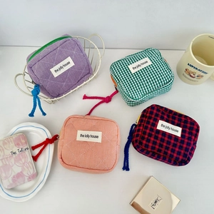 Flat lay of four colorful quilted checkered cosmetic bags with compartments and labels